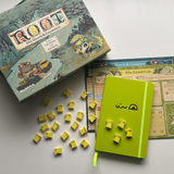 The Lizard Cult notebook next to the Riverfolk expansion box and meeples
