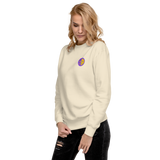 A model wearing a bone white crewneck sweatshirt with the Chancellor Mask from Oath embroidered on the left chest.