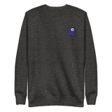 A dark grey crewneck with the Corvid Conspiracy meeple embroidered on the left chest.