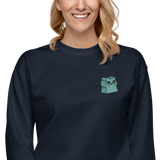Model wearing a navy crewneck sweatshirt with the Riverfolk Otter meeple embroidered on the left chest. 